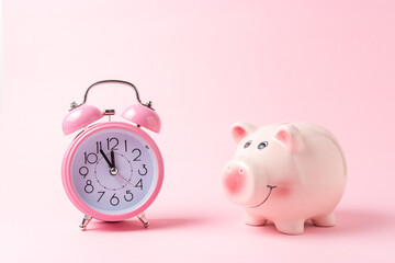 Piggy bank with alarm clock on pink background. Christmas or New Year minimal concept.