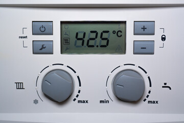 Close-up of a combi gas boiler control panel. A detailed image of the boiler's control panel featuring a digital display, buttons, and switches.