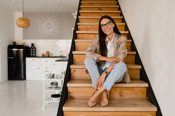 woman sitting on stairs wearing elegant beige jacket posing model in glasses