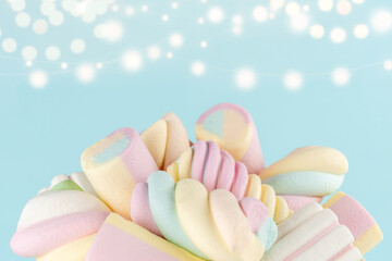 Marshmallows colorful chewy candy on blue bokeh background. Sweet holiday food concept.