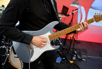 Close-up of a guitarist playing on stage. Man with musical instrument. Advertisement