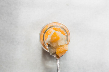 Overhead view of tangerine cheong in a spoon on a white background, top view of korean tangerine cheong, process of making tangerine cheong