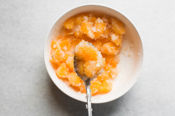 Overhead view of tangerine cheong in a spoon on a white background, top view of korean tangerine cheong, process of making tangerine cheong