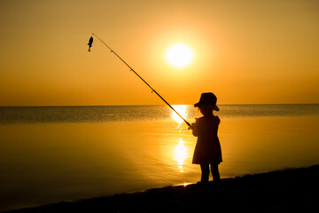 A Happy child fisherman fishing by the sea on nature silhouette travel