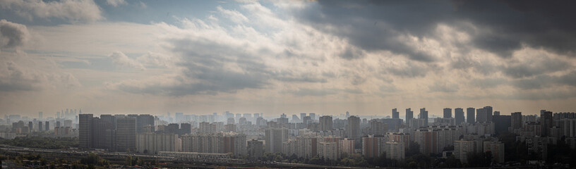 Fototapeta premium Moscow, Russia - 07.07.2024. Panorama of a big city with multi-storey residential buildings with a beautiful sky, the rays of the sun break through the clouds.
