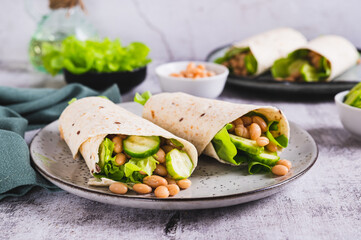 Tortilla wraps with cucumber, white beans and lettuce on a plate on a table