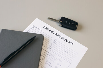 Car insurance form and car key on desk.