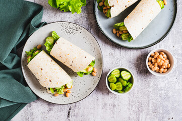 Tortilla wraps with cucumber, white beans and lettuce on a plate on a table top view