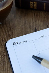 January 1st in calendar notebook with cup of coffee and holy bible. Close-up. Christian study...