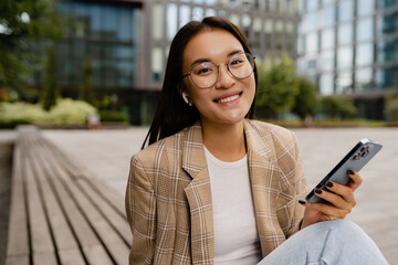 young pretty asian woman sitting outside in street doing business