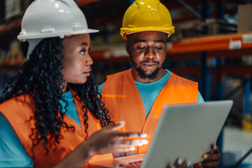 Warehouse workers using laptop discussing inventory management