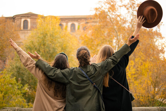 Trois amies de dos levant les bras