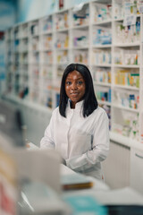 Close up of diverse pharmacist at counter in apothecary smiling at camera