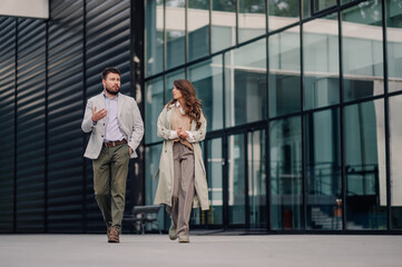 Business people walking and talking in front of modern office building