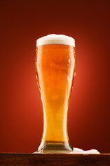 glass of beer, on wooden stand, with red background, object close-up, beer bubbles and foam