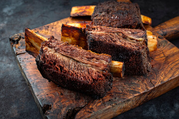 Traditional barbecue burnt chuck beef ribs marinated with spicy rub and served as close-up on an old rustic wooden board