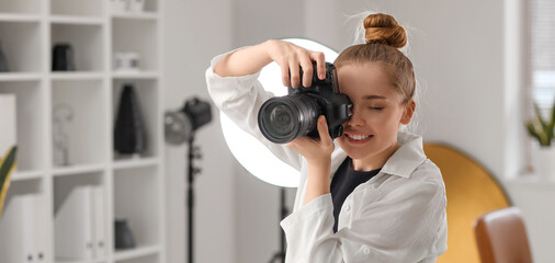 Fototapeta premium Young female photographer with professional camera working in studio