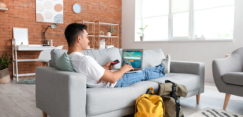Man with laptop booking tickets online at home