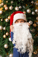 Cute little girl with Santa hat and beard near Christmas tree