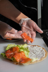 Chef prepares flatbread with salmon. Vertical photo. Quesadilla. 