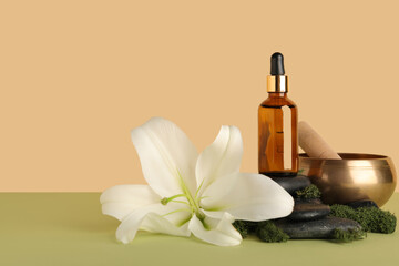 Composition with bottle of essential oil, spa accessories and lily flower on color background