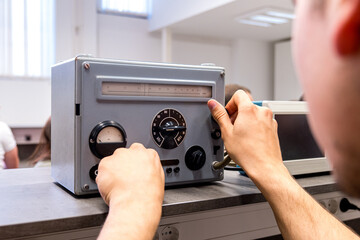 Man hand turns dials on capacitance meter