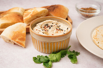 Bowl of tasty hummus with pita bread on white background
