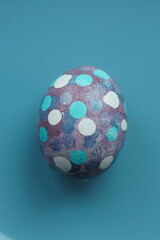 A single Easter egg decorated with colorful dots, set against a vibrant, colorful background. Perfect for spring and holiday-themed projects, capturing the festive spirit of Easter.