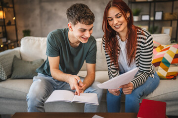 Young adult man and woman student help each other to study for exam