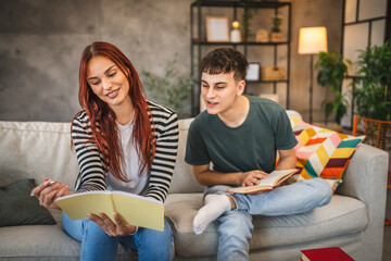 Young adult man and woman student help each other to study for exam