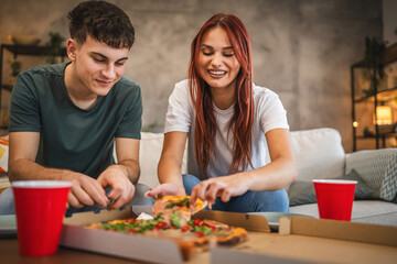 Adult couple take a pizza from pizza box ready for hanging out at home