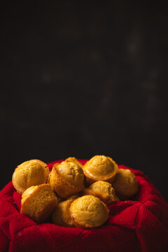 tiny cornbread muffins in a red towel-lined basket in front of a black background