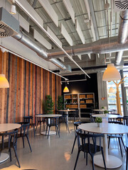 Modern cafe interior featuring sleek furniture, wooden panel walls, and industrial ceiling design with unique lighting.