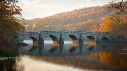 Fototapeta premium Stone Arch Bridge Reflecting in a Still Lake Surrounded by Fall Foliage