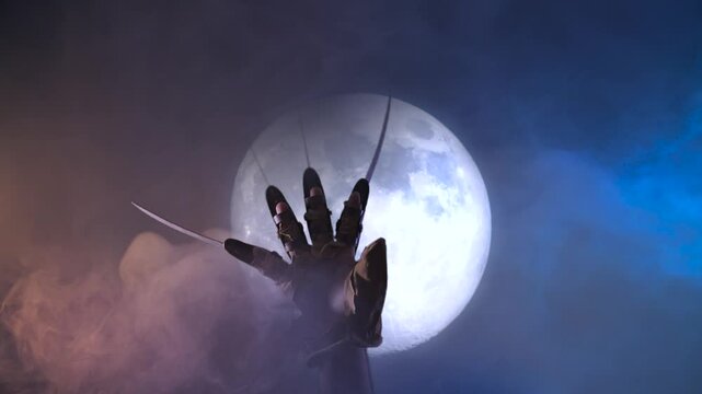 scary  a monster hand  with metallic  claws on a dark moon Halloween background