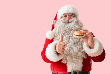 Santa Claus with tasty burger showing thumb-up on pink background