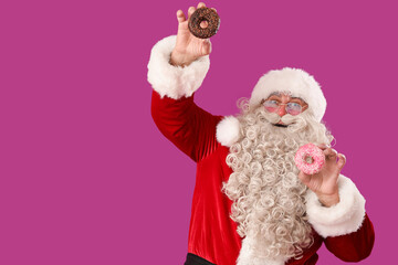 Happy Santa Claus with tasty donuts on purple background