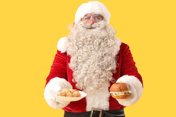 Santa Claus with tasty falafel balls and burger on yellow background