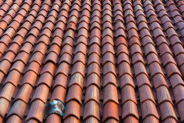 Close up of a terracotta tile roof with textured clay shingles in warm earthy tones. Concept of traditional Mediterranean architecture and durable building materials. High quality photo