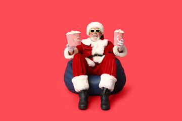 Happy Santa Claus in 3D glasses with buckets of tasty popcorn on red background
