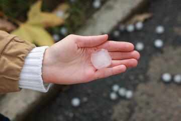 Woman holding hail grain after thunderstorm outdoors, closeup