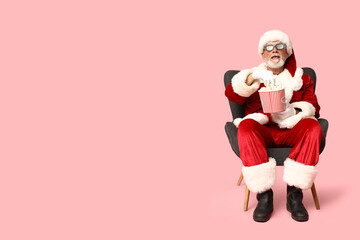 Santa Claus in 3D glasses with bucket of tasty popcorn on pink background