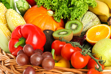Different fresh fruits and vegetables in wicker basket, closeup