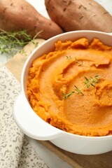 Delicious mashed sweet potatoes in pot and vegetables on table, closeup