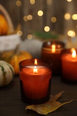 Burning candles and autumn decor on wooden table, closeup