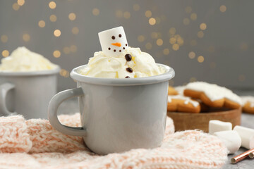 Funny snowman made with marshmallow and whipped cream in cup of hot drink served on background...