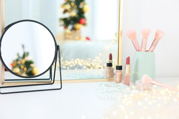 Makeup brushes, cosmetics and mirror on white table indoors