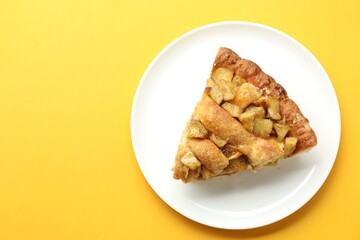 Slice of homemade apple pie on orange background, top view. Space for text