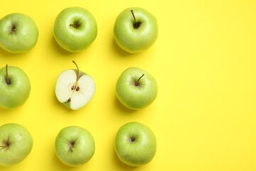 Flat lay composition with half of apple surrounded by ones on yellow background. Space for text