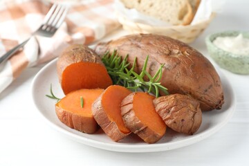 Tasty cooked sweet potatoes and rosemary on white table, closeup